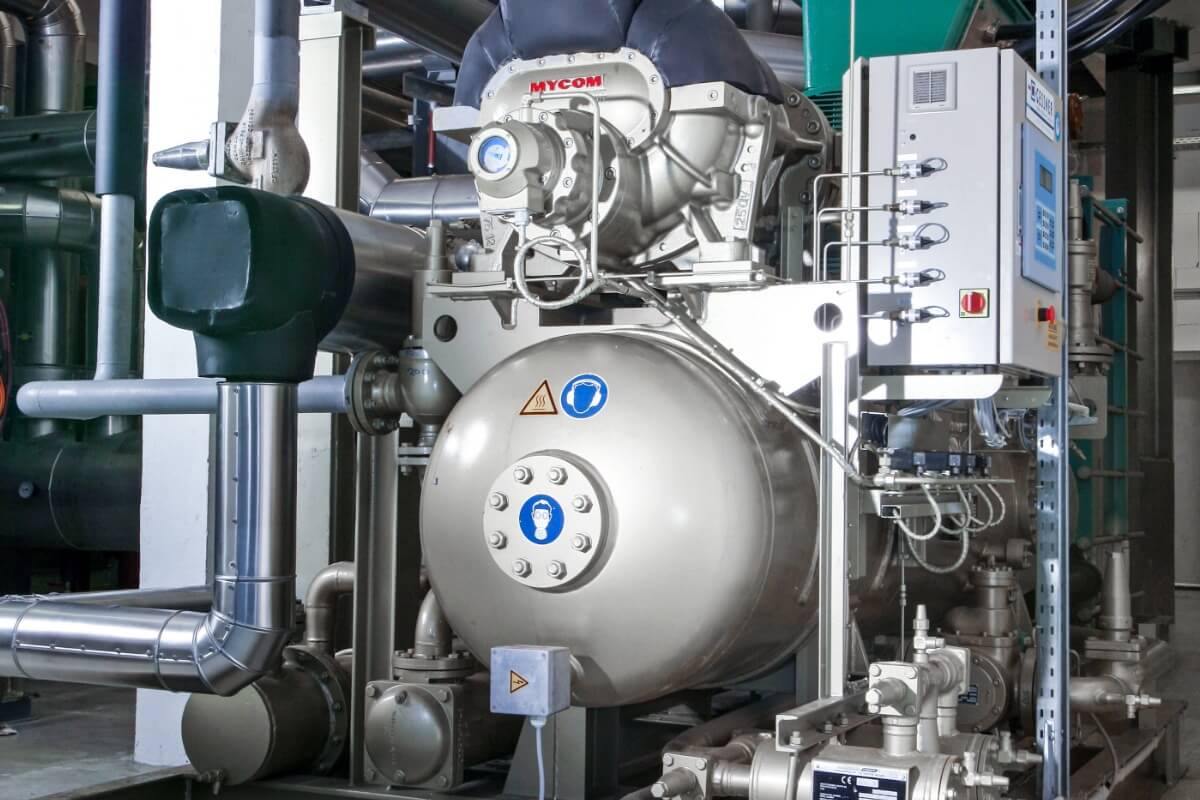 Industrielle Maschinenanlage mit Schläuchen und Metallteilen in einem technischen Raum.
