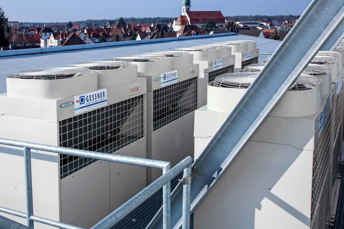 Industrie-Klimaanlagen auf einem Dach mit Stadtansicht im Hintergrund. Effiziente Kühltechnik für große Gebäude.